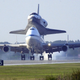 A 747 jet carries the space shuttle to an airport runway